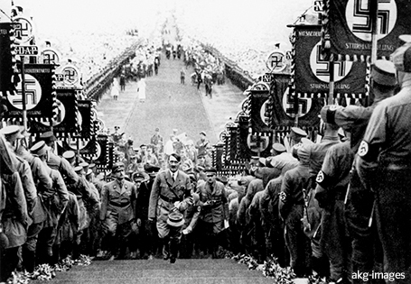 Höhepunkt der Inszenierung: Adolf Hitler durchschreitet auf dem „Mittelweg“ die Menschenmassen und betritt die Rednertribüne. Propagandaaufnahme, 1934