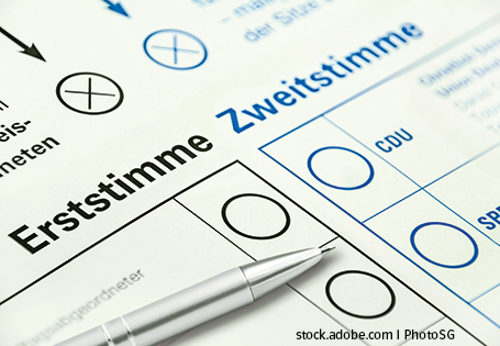 Zu sehen ist der Ausschnitt eines Stimmzettels für die Wahl mit den Begriffen "Erststimme" und "Zweitstimme". Auf dem Zettel liegt ein silberner Kugelschreiber, bereits zum Ankreuzen der Stimmen.