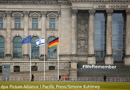 Reichstag Berlin mit Fahnen auf Halbmast und weißem Schriftzug #We Remember