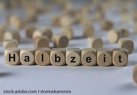 Holzwürfel mit den Buchstaben H a l b z e i t in einer Reihe auf einer weißen Fläche